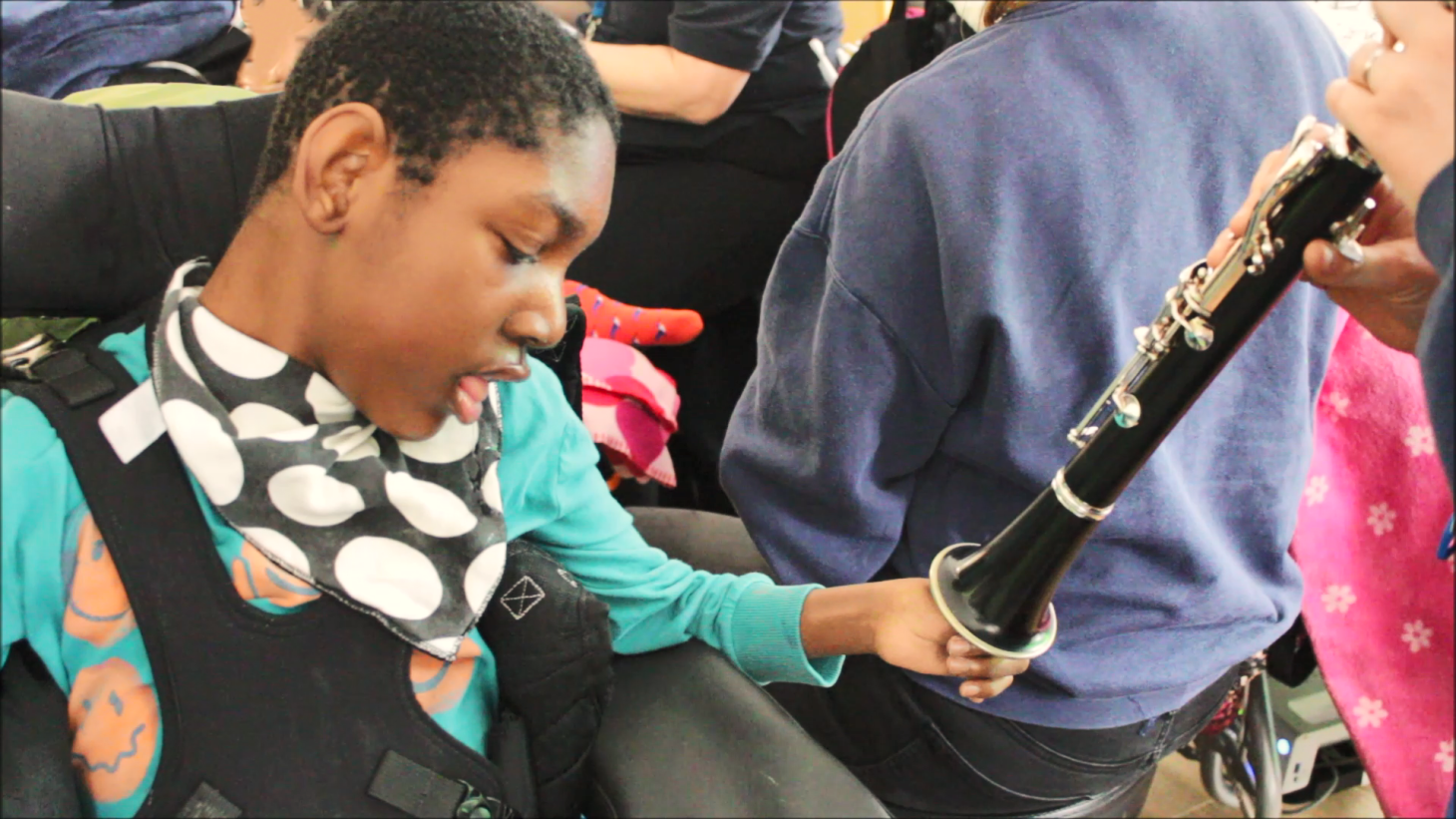 Young person enjoying listening to and touching a clarinet with music therapist