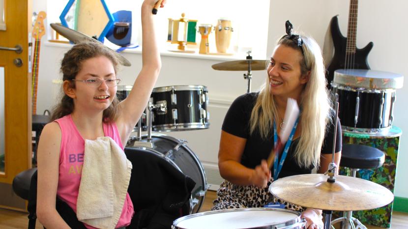 Young person playing the drums with Music Therapist