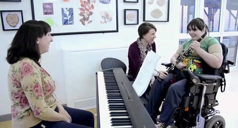 Catherine: young woman plays guitar with two music therapists