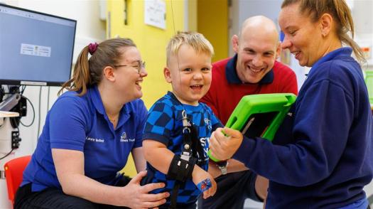 Reuben smiling whilst using a device