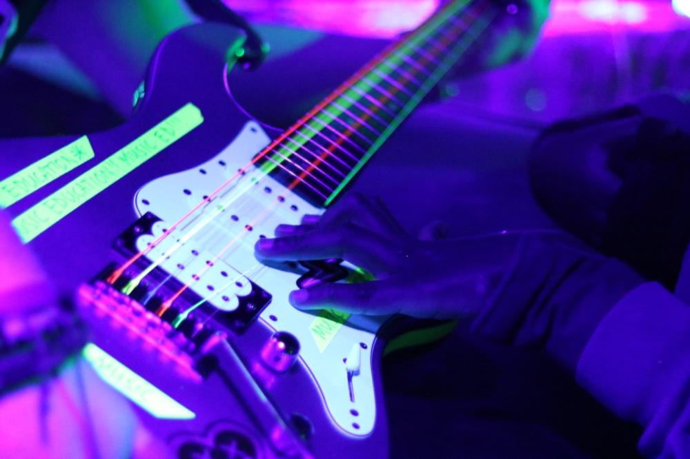 hands on a guitar in a UV tent