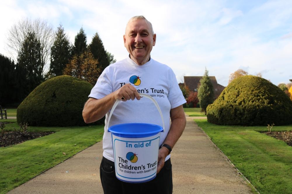 A volunteer holding a collection bucket and smiling