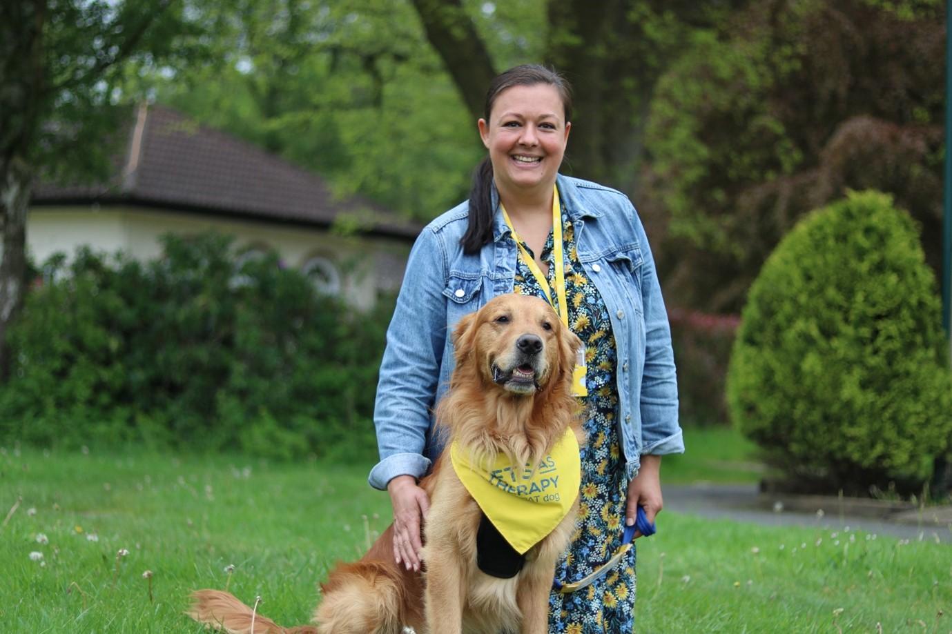 Lee and her PAT dog Mac, sitting outside on the grass