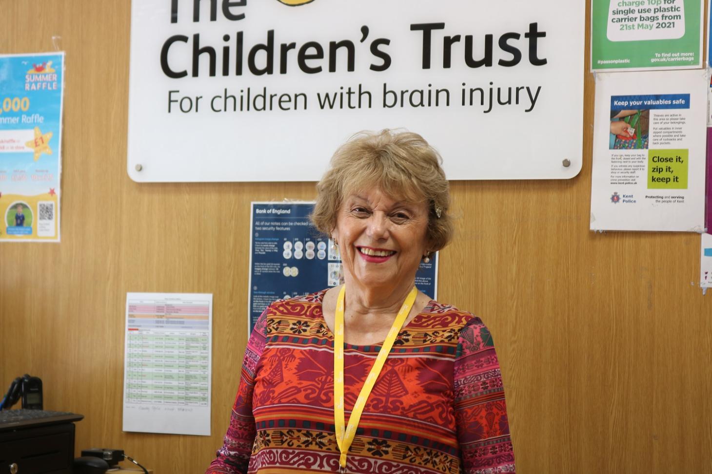 Pauline stands behind the till at The Children's Trust charity shop