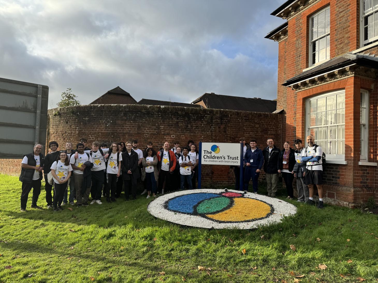 A group of students standing outside The Children's Trust smiling at the camera