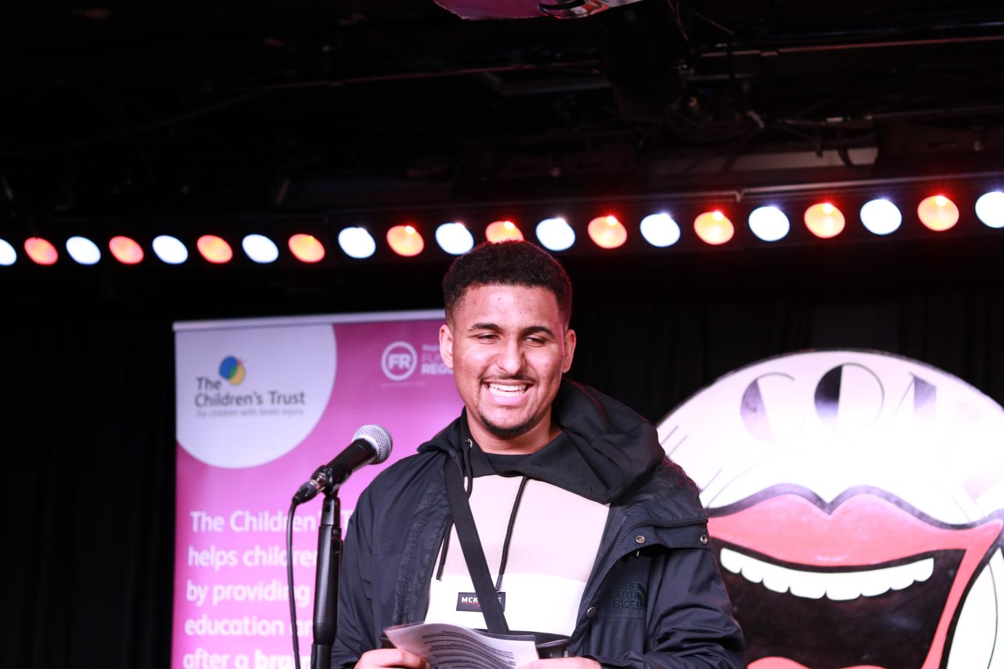 Zac on stage in front of The Comedy Store logo