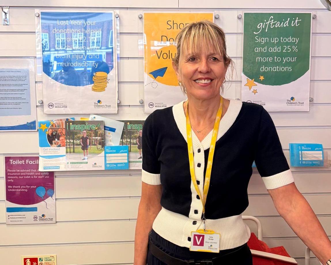 Volunteer charity standing smiling in our charity shop