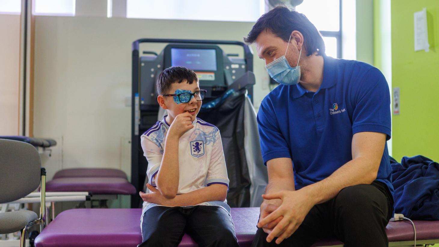 Child takes part in a therapy session with a therapist, sitting together and talking in a clinic.