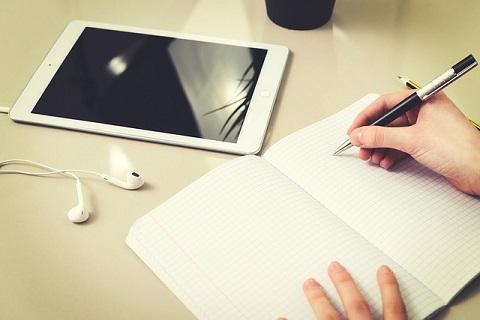 a hand holds a pen writing in a notebook