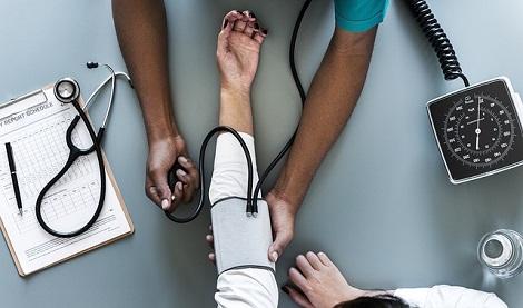 patient arm with blood pressure cuff being held by a doctor's arm