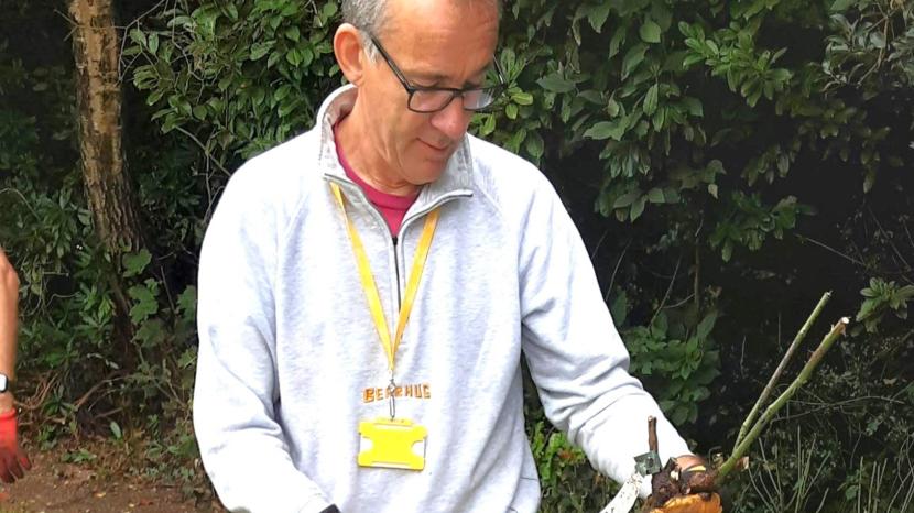 Nick is outside wearing gloves and holding gardening tools