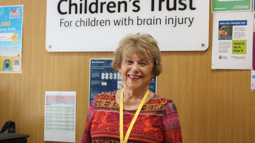 Pauline stands behind the till at The Children's Trust charity shop