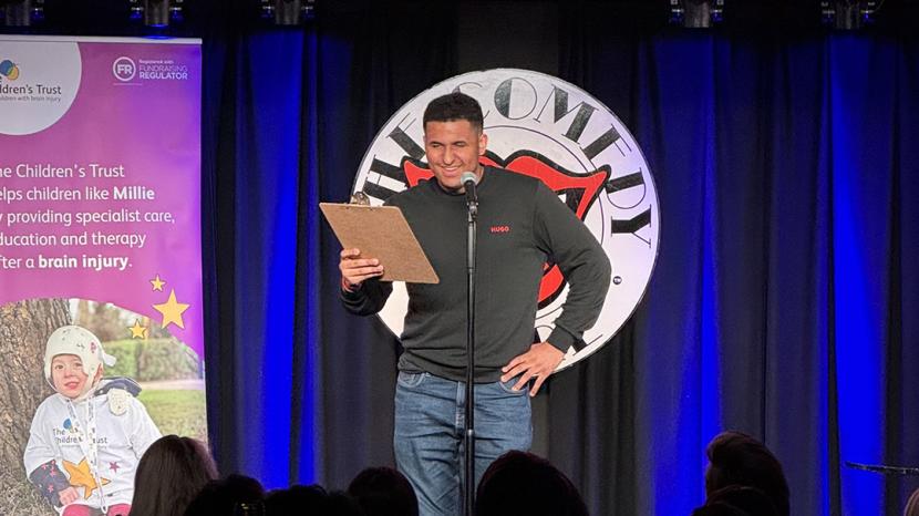 Zac on stage in front of The Comedy Store sign