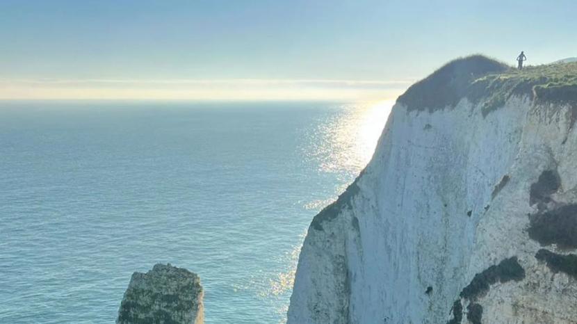 beautiful blue sky with sun reflecting on the baby blue sea surrounding white chalky cliffs