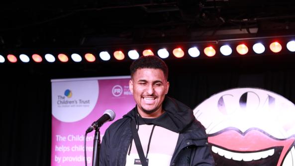 Zac on stage in front of The Comedy Store logo