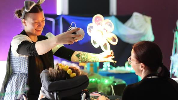 performer holding up a lit-up flower in front of a child